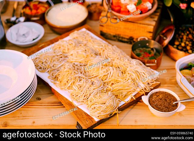 Spaghetti on a wooden plank for cutting with cooked meals and clean plates. High quality photo