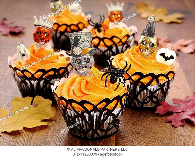Halloween cupcakes on an oak table with autumnal leaves