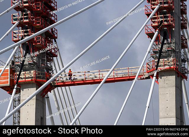 15 March 2023, Saxony-Anhalt, Magdeburg: A worker walks across a connecting footbridge between the pylons of the new bridge construction in Magdeburg