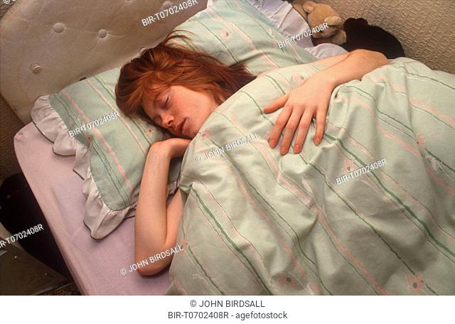 Teenage girl sleeping in bed