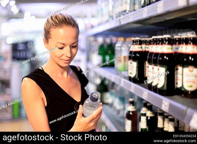 Woman choosing mineral water in grocery store