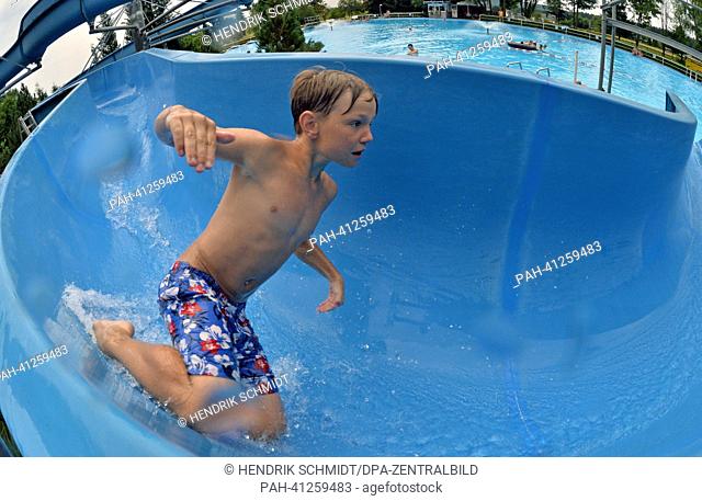 A boy slides into the water on the 75 m long waterslide in the bath of Rebesgruen, Germany, 24 July 2013. This weekend the 17th German water sliding...