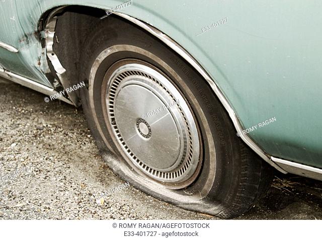 Flat tire on an old rusty 1979 Chrysler Cordoba car