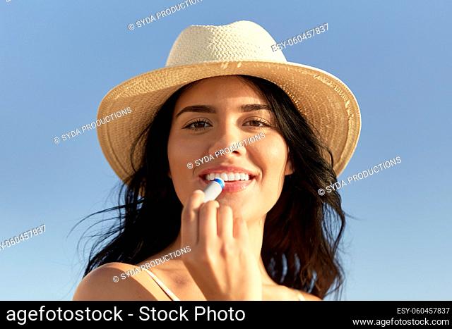 smiling woman in bikini with lip balm on beach