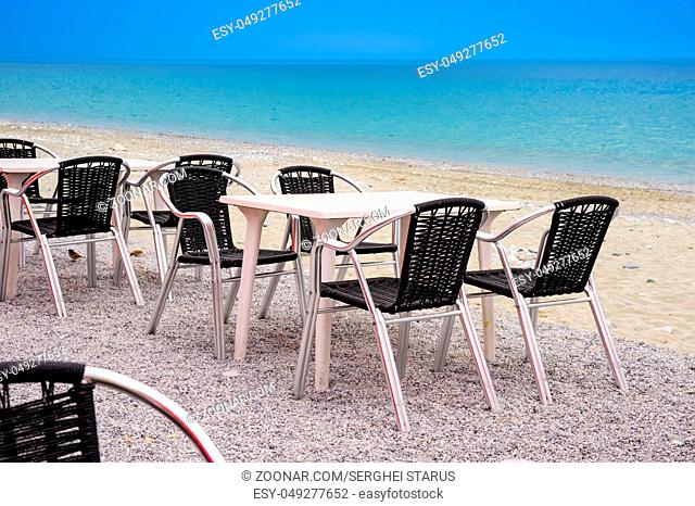 Beach cafe with empty tables and chairs placed at the sea waterfront