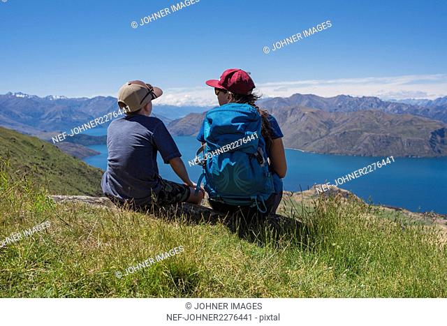 Boy with woman looking at lake in mountains