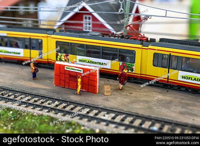 10 May 2022, Baden-Wuerttemberg, Rheinstetten: A model of the ""Hofladentram"" stands in a diorama on a platform on which a ""Hofladen-Packstation"" is set up