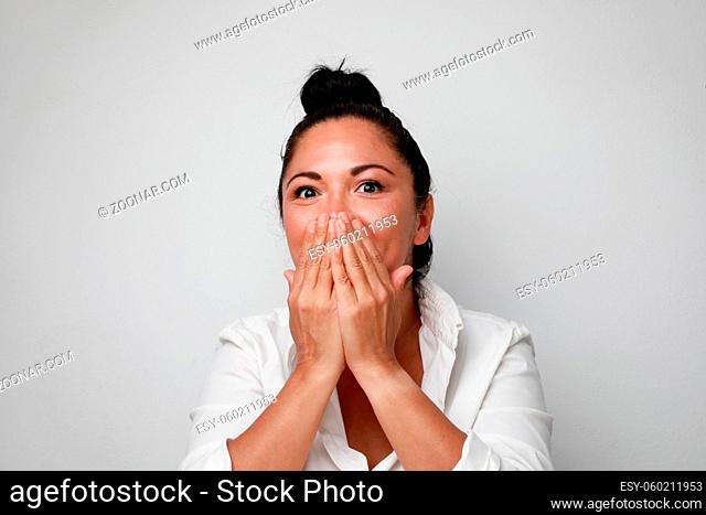 Image of young surprised woman smiling and covering her face. High quality photo