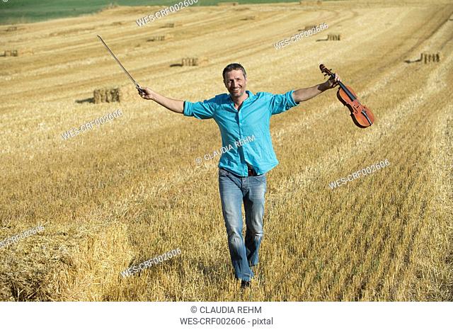Germany, Bavaria, Starnberg Region, Man playing violin in field