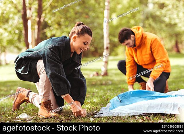 happy couple setting up tent outdoors