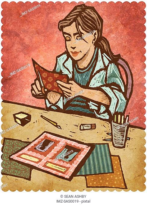 A woman cutting papers and creating a scrapbook
