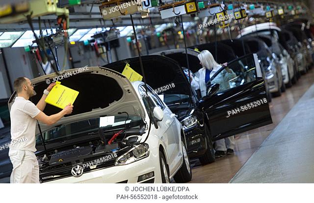 A staff member of car manufacturer Volkswagen AG (VW) inspects a car during the final inspection at the company's assembly plant in Wolfsburg, Germany