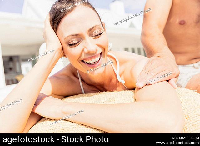 Man stroking happy woman lying on sul lounger