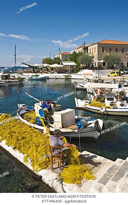 A fisherman mending nets on the quay side in the little harbour at Ayios Nikolaos, in The Outer Mani, Southern Peloponnese, Greece