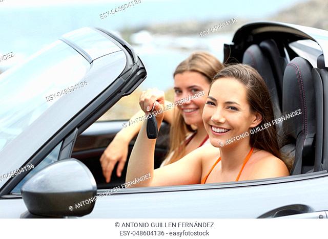 Car renters holding a key looking at you on vacations
