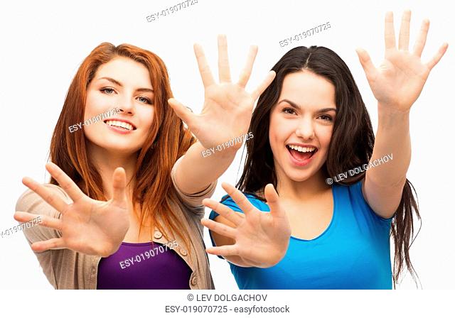 happiness and people concept - two smiling girls showing their palms