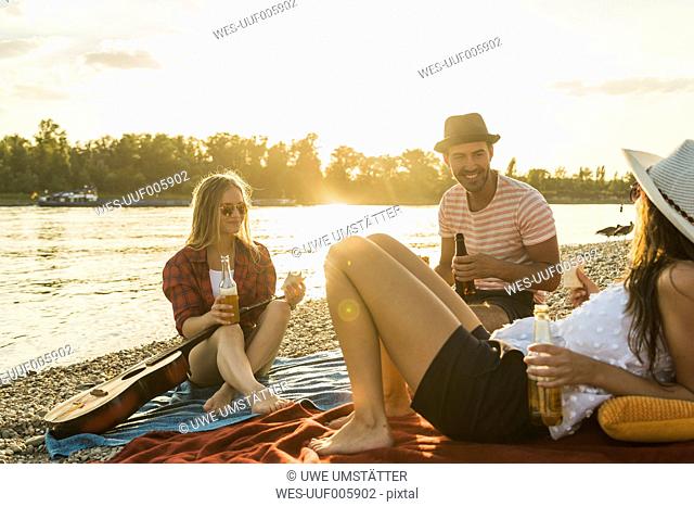 Friends relaxing at the riverside at sunset