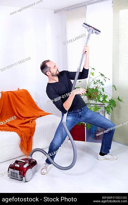 A man pretending to be a guitarist with a vacuum cleaner