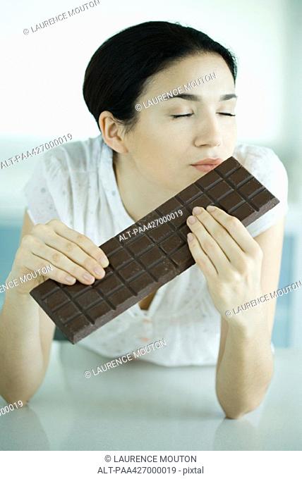 Woman holding large bar of chocolate, eyes closed