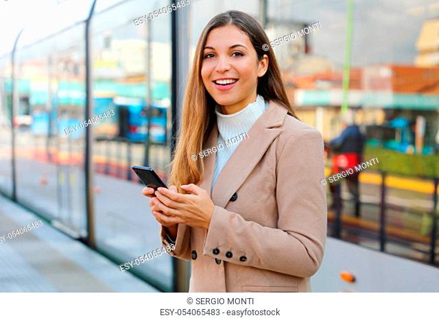 People and public transport. Happy beautiful woman holding cellular at tram stop