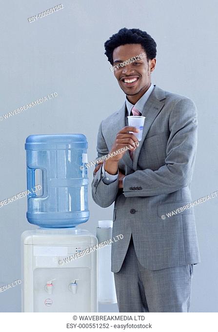 Afro-American businessman drinking from a water cooler in office