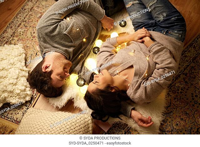 happy couple with garland lying on floor at home
