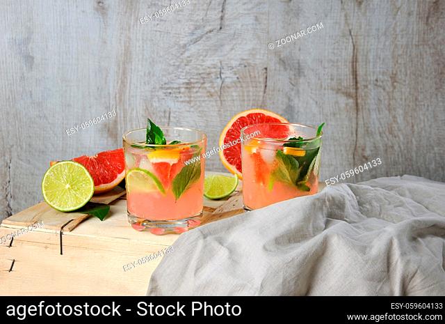 Cocktail of juice squeezed red grapefruit and leaves of delicate lemon basil, lime slices and chilled ice cubes