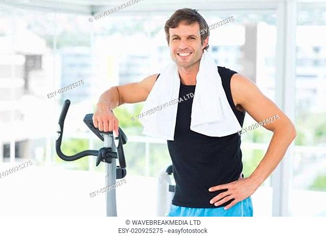 Smiling man standing at spinning class in bright gym
