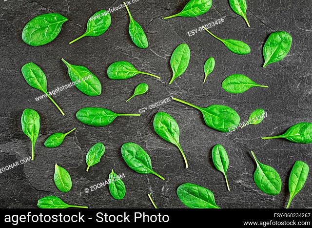 Corn salad Valerianella locusta leaves arranged in pattern over black slate like board - overhead shot. Healthy green leaf food concept