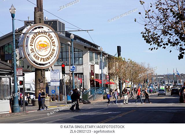 People stroll at Fishermans’s Wharf in San Francisco, California. Famous Fisherman Wharf circular sign in the famous tourist section of San Francisco