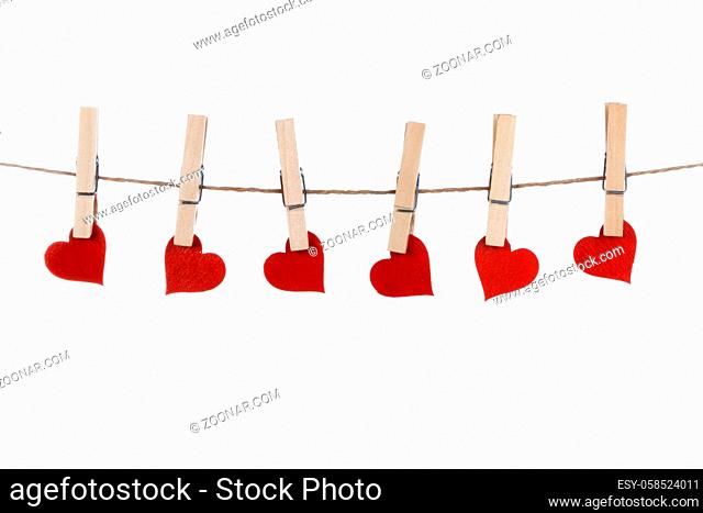 Clothes pegs and red paper hearts on rope isolated on white background