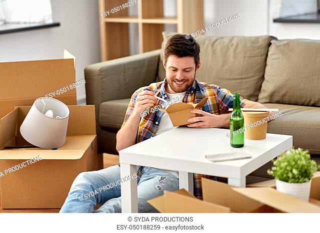 smiling man eating takeaway food at new home
