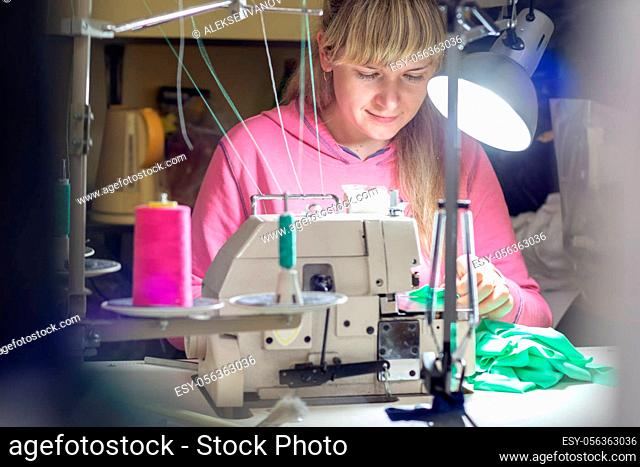 Girl works by light lamp behind industrial sewing machine