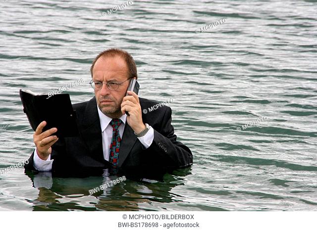 businessman withmobile phone and diarykeep his head above water