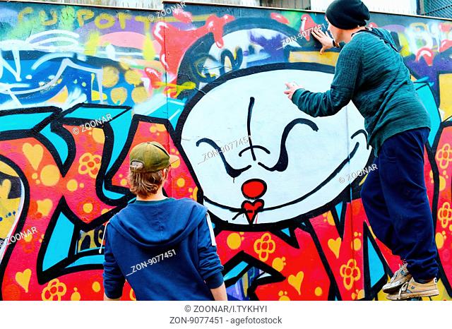 LISBON, PORTUGAL - DECEMBER 23, 2014: Boys painting graffiti on the wall in Lisbon.Along with London, Berlin, New York and others