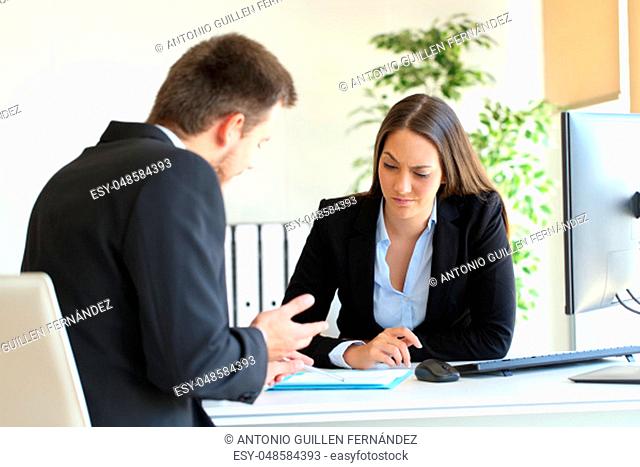 Bad businessman trying to convince to a suspicious client during a difficult negotiation in a desktop at office