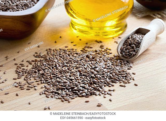 Flax seeds on a wooden table, with flax seed oil in the background