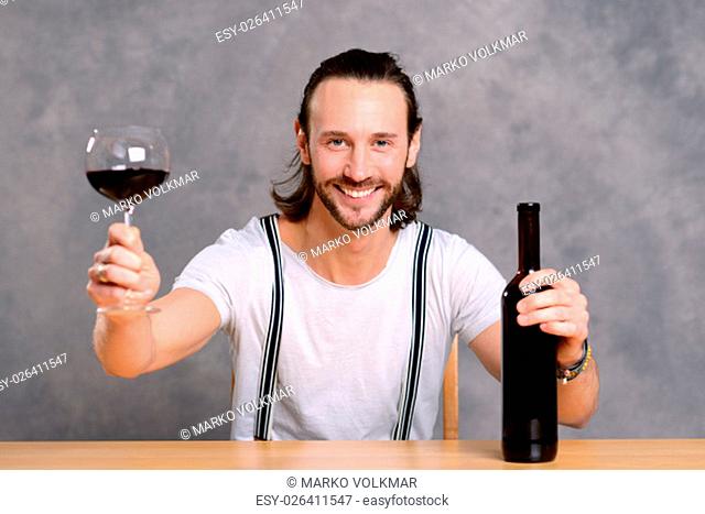 young man in front of gray background drinking red wine