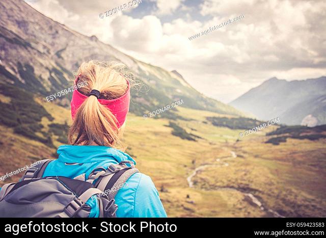 Woman in sportswear and with backpack enjoys the view in the mountains