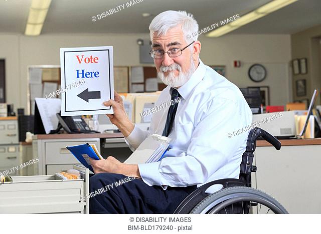Caucasian businessman holding voting sign in office