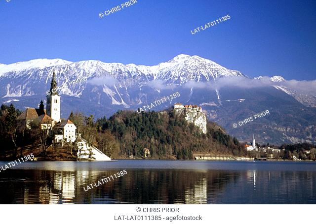 Bled Castle. Blejski Grad. Island in lake. Church of the Assumption. Baroque style. Tower. Mountains. Julian alps. Snow