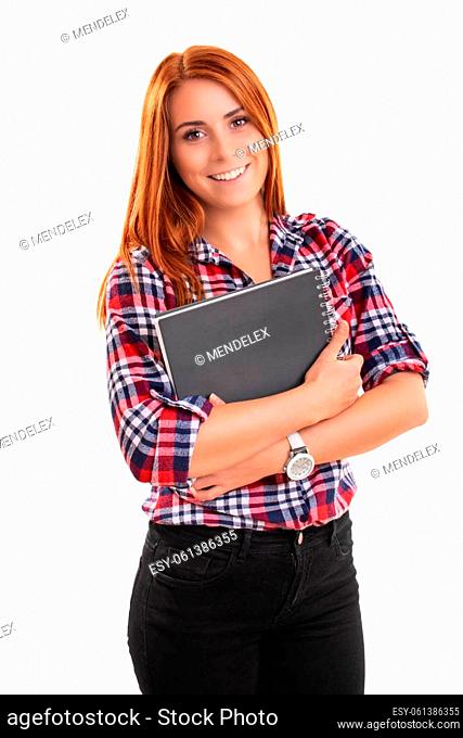 Smiling young redhead woman in plaid shirt holding a notebook in front of her, isolated on white background. Education, study, exams, achievement concept