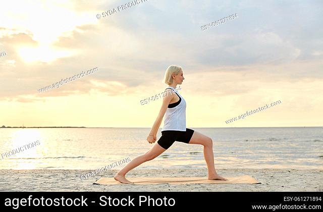 happy woman doing yoga warrior pose on beach