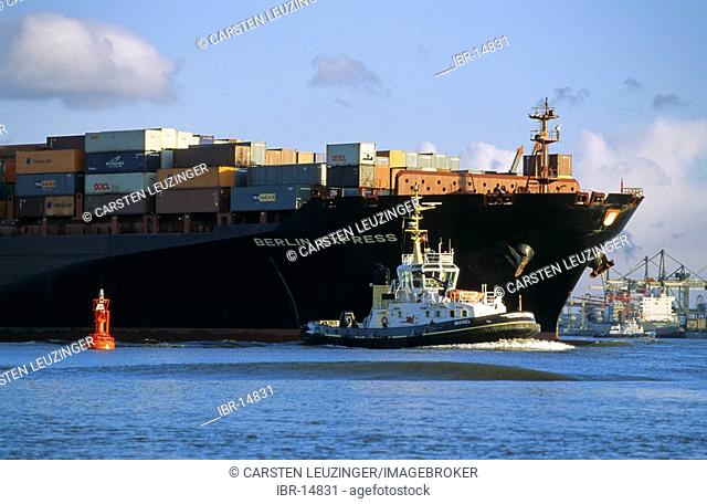 Tug boat escorting a huge container ship on river Elbe at Hamburg Germany