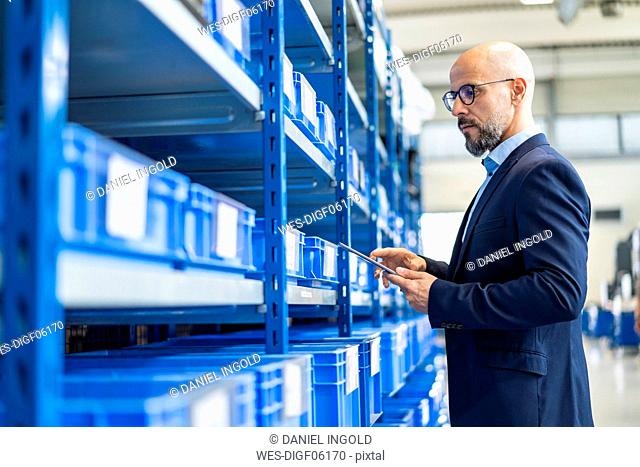 Businessman with tablet in factory storehouse