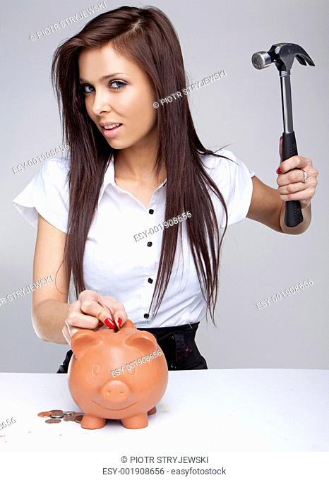 Young woman breaking a piggy bank