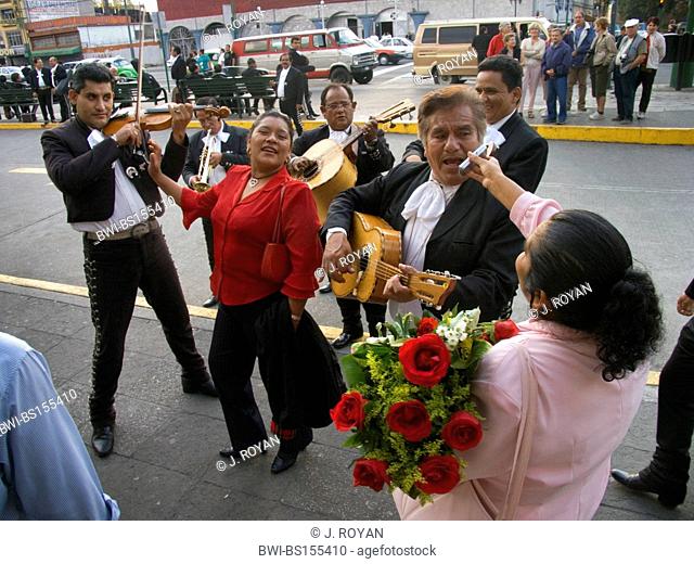A woman asks a musician to sing on her cell phone during a 'serenata'. Mariachis in Plaza Garibaldi, Mexico, Mexico City