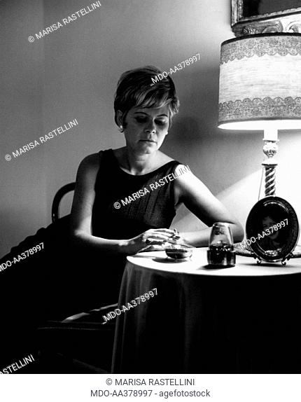 Lianella Carell smoking a cigarette. Italian actress and journalist Lianella Carell smoking a cigarette sitting on a chair. Rome, 1963