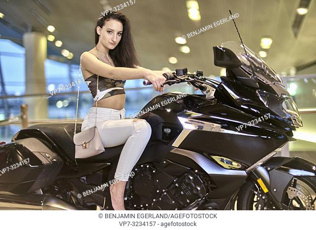 fashionable woman sitting on motorbike, indoors