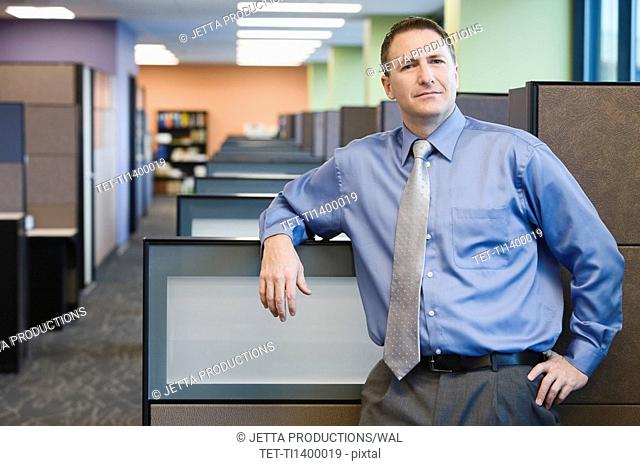 Businessman leaning on cubicle wall